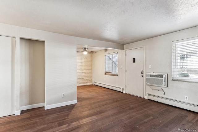 foyer with dark wood-type flooring, a wall mounted AC, a textured ceiling, and baseboard heating