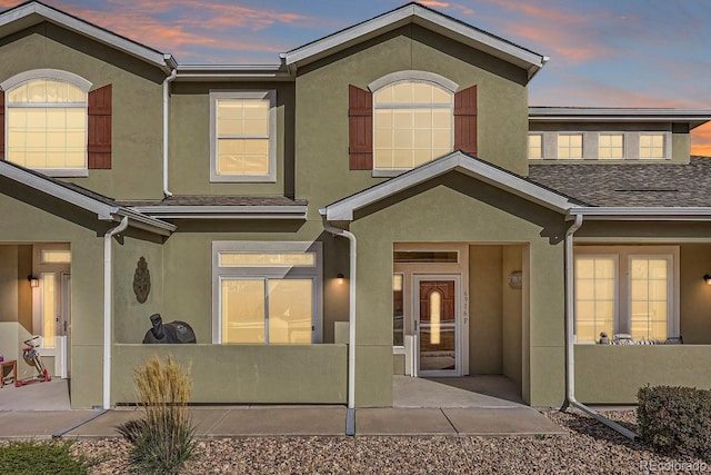 6916 Crestop Pl Unit F, Parker, CO 80138 - exterior entry at dusk featuring stucco siding and a patio