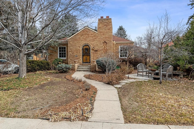 view of front facade featuring a chimney, a patio, and brick siding