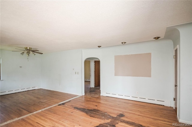 1195 Boston St, Aurora, CO 80010 - spare room featuring a baseboard radiator, arched walkways, wood finished floors, and baseboard heating