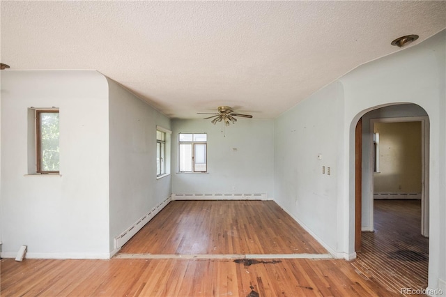 1195 Boston St, Aurora, CO 80010 - empty room featuring arched walkways, a textured ceiling, a ceiling fan, baseboard heating, and wood finished floors