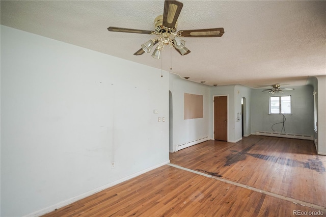 1195 Boston St, Aurora, CO 80010 - unfurnished living room with baseboard heating, arched walkways, hardwood / wood-style floors, a ceiling fan, and a textured ceiling