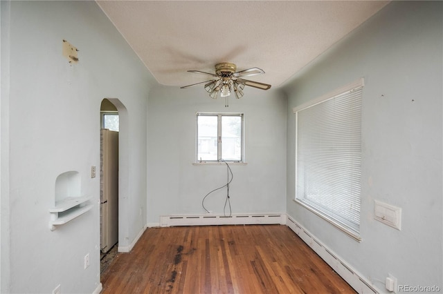 1195 Boston St, Aurora, CO 80010 - spare room with arched walkways, a baseboard heating unit, a ceiling fan, and wood finished floors