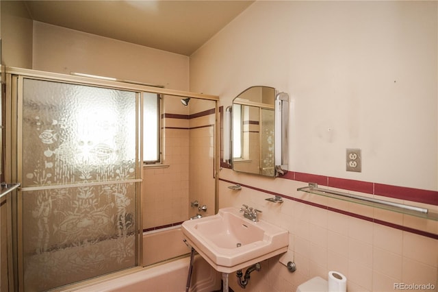 1195 Boston St, Aurora, CO 80010 - bathroom featuring bath / shower combo with glass door, a sink, and tile walls