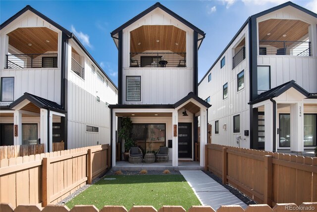 back of house featuring a balcony, board and batten siding, and fence