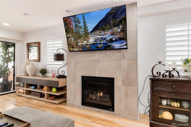 living room featuring recessed lighting, wood finished floors, and a tiled fireplace