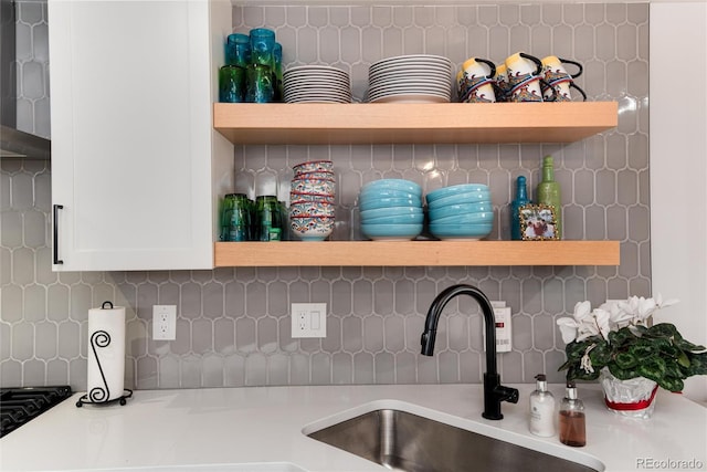 details featuring decorative backsplash, open shelves, light countertops, and a sink