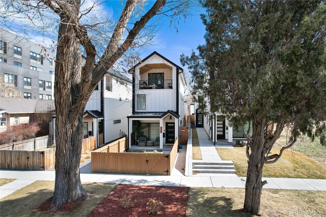 view of front of home featuring a fenced front yard, board and batten siding, and a balcony