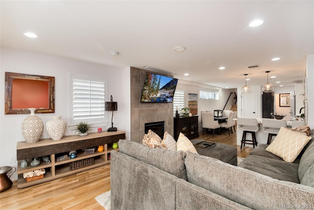 living room with light wood finished floors, visible vents, recessed lighting, and a fireplace