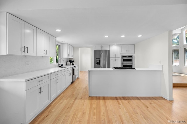 11241 E Cimmarron Dr, Englewood, CO 80111 - kitchen with appliances with stainless steel finishes, light wood finished floors, backsplash, white cabinets, and recessed lighting