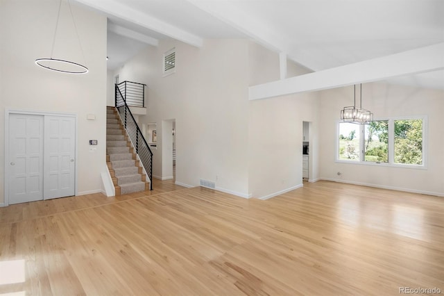 11241 E Cimmarron Dr, Englewood, CO 80111 - unfurnished living room with high vaulted ceiling, a chandelier, beamed ceiling, stairs, and light wood-style flooring