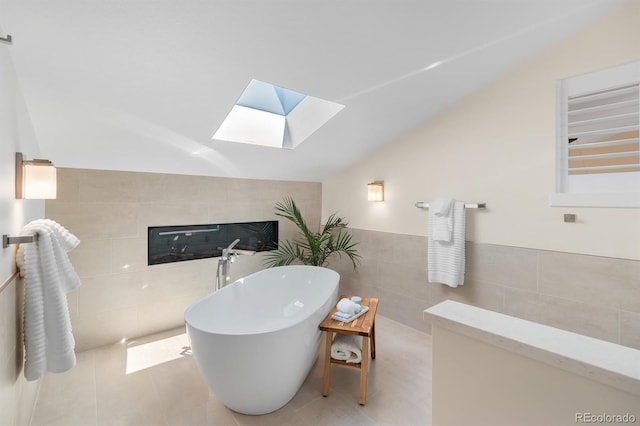 11241 E Cimmarron Dr, Englewood, CO 80111 - full bathroom with tile walls, a skylight, vaulted ceiling, a soaking tub, and a tiled fireplace