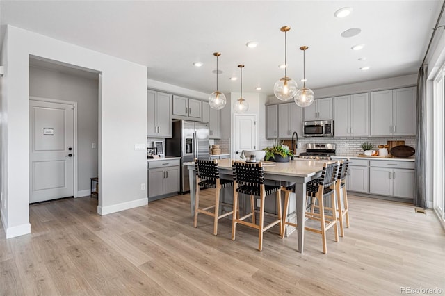 16498 W 92nd Pl, Arvada, CO 80007 - kitchen with stainless steel appliances, gray cabinetry, light countertops, decorative backsplash, and light wood-style flooring