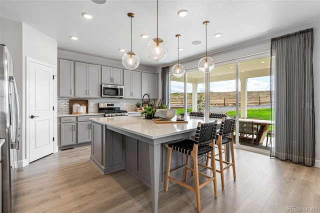 16498 W 92nd Pl, Arvada, CO 80007 - kitchen featuring gray cabinets, appliances with stainless steel finishes, light countertops, light wood-style floors, and backsplash