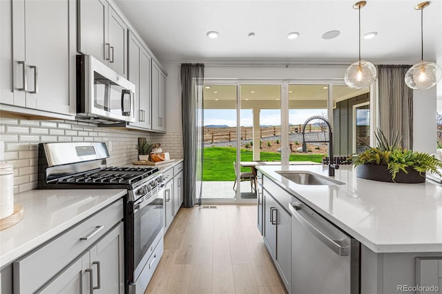 16498 W 92nd Pl, Arvada, CO 80007 - kitchen featuring appliances with stainless steel finishes, gray cabinets, light wood-type flooring, backsplash, and light stone counters