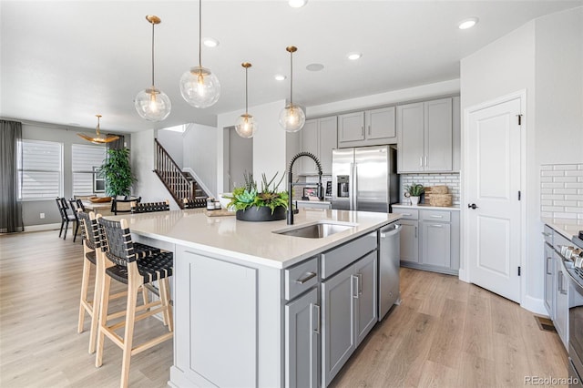 16498 W 92nd Pl, Arvada, CO 80007 - kitchen featuring appliances with stainless steel finishes, gray cabinetry, tasteful backsplash, light wood finished floors, and recessed lighting