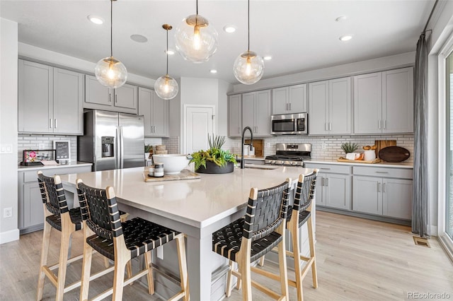 16498 W 92nd Pl, Arvada, CO 80007 - kitchen featuring stainless steel appliances, gray cabinets, tasteful backsplash, a kitchen breakfast bar, and recessed lighting