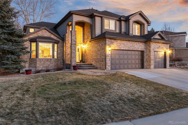 view of front of home with a yard, concrete driveway, brick siding, and a garage