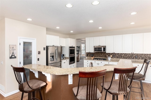 kitchen featuring light wood-style floors, tasteful backsplash, appliances with stainless steel finishes, and white cabinets