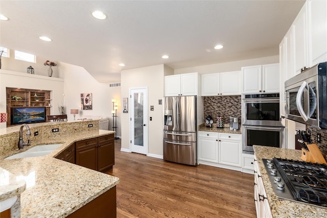 kitchen with visible vents, decorative backsplash, dark wood-style flooring, stainless steel appliances, and a sink