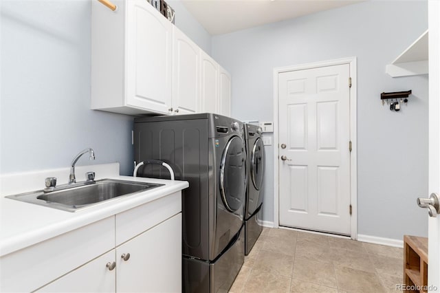 clothes washing area with light tile patterned flooring, a sink, baseboards, independent washer and dryer, and cabinet space