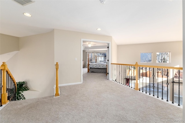 hallway with carpet floors, recessed lighting, visible vents, and an upstairs landing