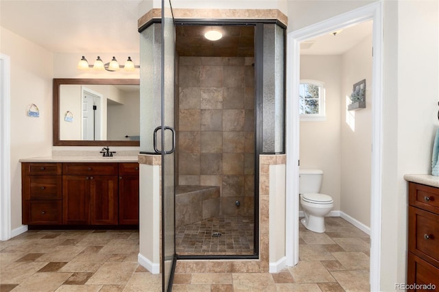 bathroom featuring toilet, stone finish flooring, a stall shower, and vanity