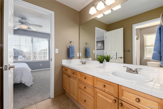 ensuite bathroom featuring ceiling fan, tile patterned floors, a sink, and double vanity