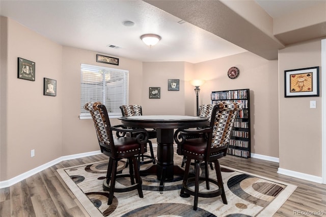 dining area with wood finished floors, visible vents, and baseboards