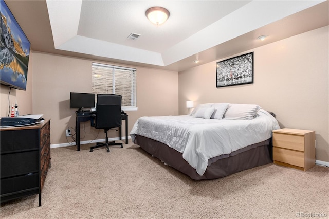 carpeted bedroom featuring a tray ceiling, visible vents, and baseboards