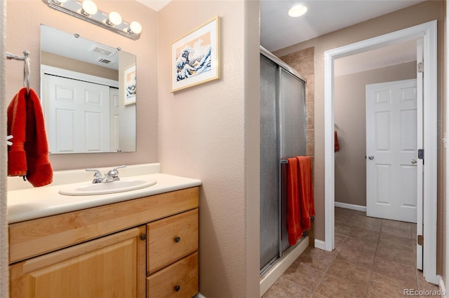 bathroom with a stall shower, vanity, baseboards, and tile patterned floors