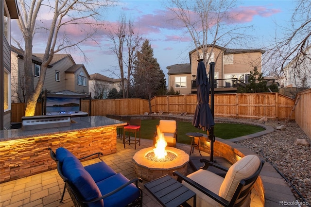 view of patio featuring a fenced backyard, a fire pit, an outdoor kitchen, and outdoor dry bar