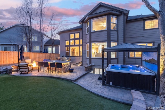 rear view of house with a patio, an outdoor fire pit, fence, outdoor dry bar, and a hot tub