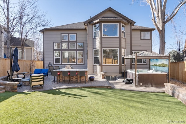 back of house with a hot tub, a lawn, outdoor dry bar, fence, and a patio area