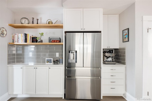 kitchen with white cabinets, stainless steel fridge, and backsplash