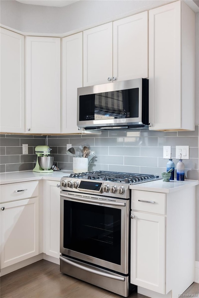 kitchen featuring white cabinetry, hardwood / wood-style flooring, tasteful backsplash, and appliances with stainless steel finishes