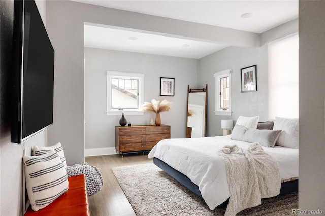 bedroom with multiple windows, wood-type flooring, and a barn door