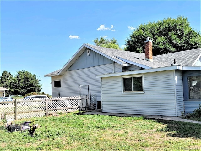 rear view of house featuring a chimney and a shingled roof