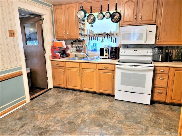 kitchen featuring white appliances, a sink, light countertops, stone finish flooring, and brown cabinetry