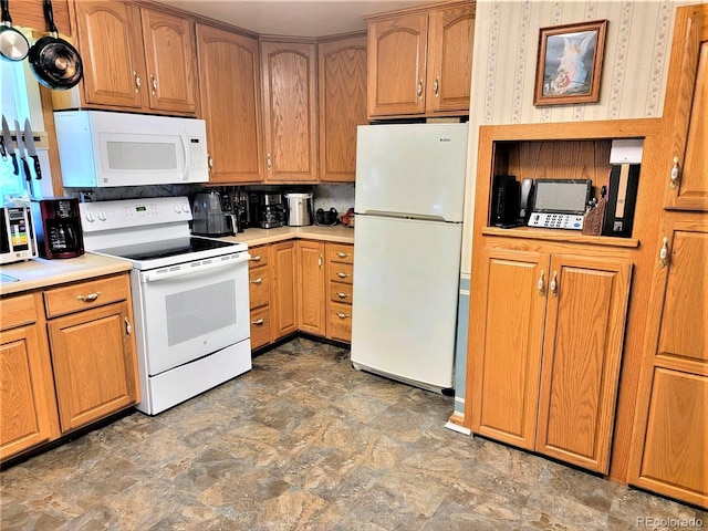 kitchen with white appliances, stone finish floors, light countertops, and brown cabinetry