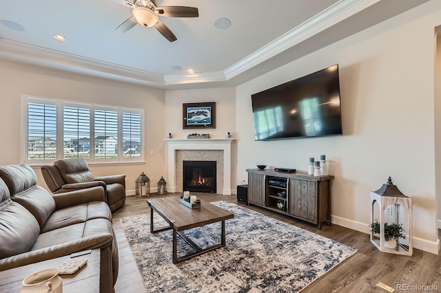 4536 Shady Path Ln, Castle Rock, CO 80104 - living room featuring ornamental molding, ceiling fan, wood finished floors, a tray ceiling, and a glass covered fireplace
