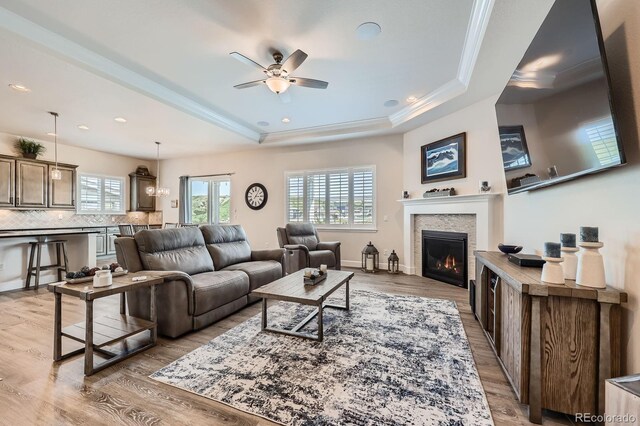 4536 Shady Path Ln, Castle Rock, CO 80104 - living room with a tray ceiling, ceiling fan, a tile fireplace, light wood-style floors, and crown molding