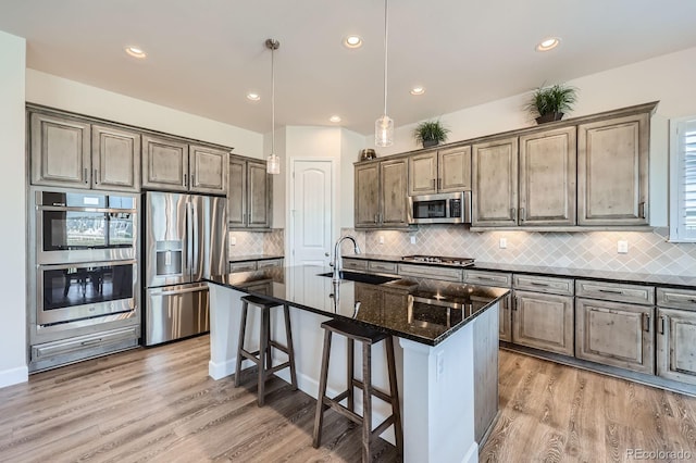 4536 Shady Path Ln, Castle Rock, CO 80104 - kitchen with appliances with stainless steel finishes, a sink, a kitchen bar, a kitchen island with sink, and decorative backsplash