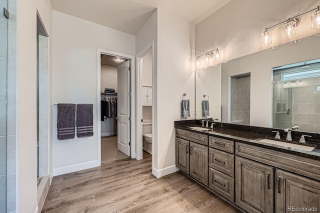 4536 Shady Path Ln, Castle Rock, CO 80104 - bathroom featuring a stall shower, wood finished floors, double vanity, toilet, and a walk in closet