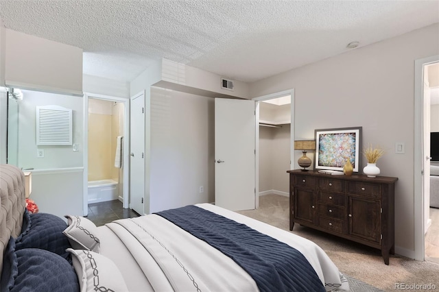 3550 S Harlan St Unit 177, Denver, CO 80235 - bedroom featuring a spacious closet, a textured ceiling, light colored carpet, ensuite bathroom, and a closet