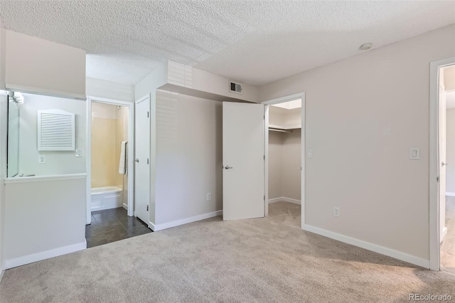 3550 S Harlan St Unit 177, Denver, CO 80235 - unfurnished bedroom with carpet floors, a textured ceiling, a walk in closet, ensuite bathroom, and baseboards