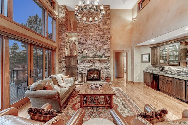 living room with an inviting chandelier, a fireplace, light hardwood / wood-style floors, and a high ceiling