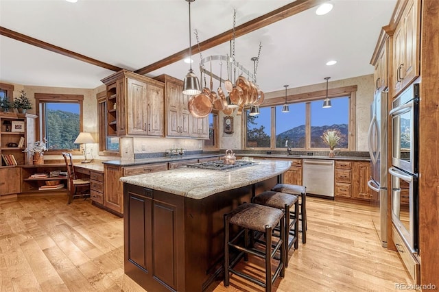 kitchen with a center island, dark stone counters, a mountain view, stainless steel appliances, and light hardwood / wood-style floors