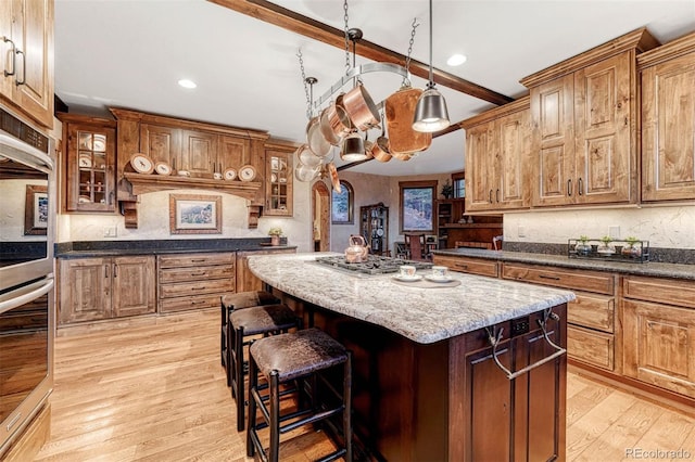 kitchen featuring a kitchen bar, a center island, appliances with stainless steel finishes, dark stone counters, and light hardwood / wood-style floors