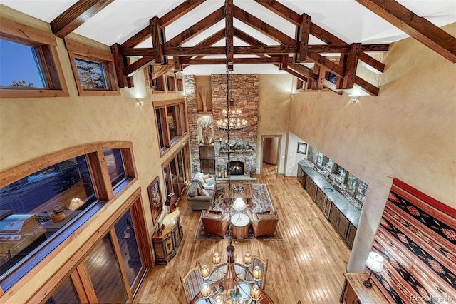 living room with beam ceiling, light wood-type flooring, a notable chandelier, and a fireplace